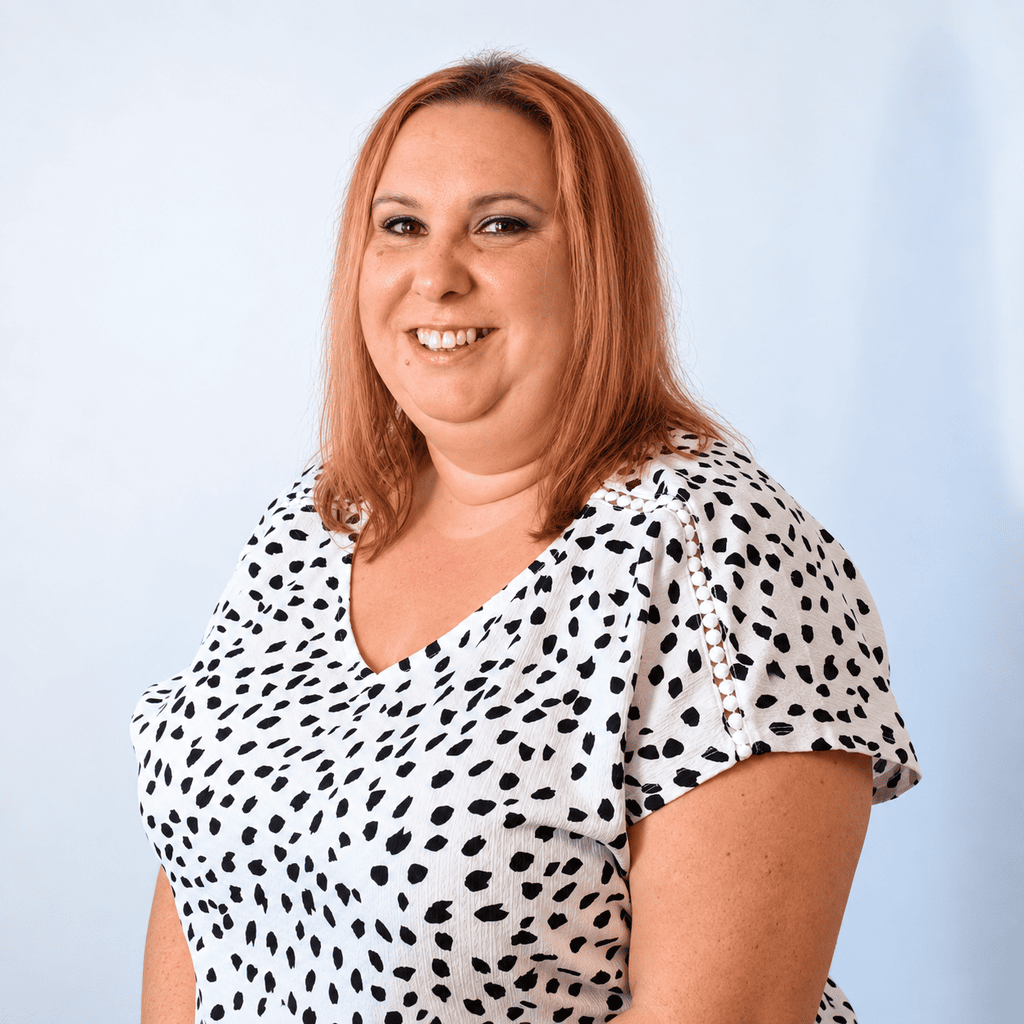 Smiling woman with red hair in a polka dot top for About us page.