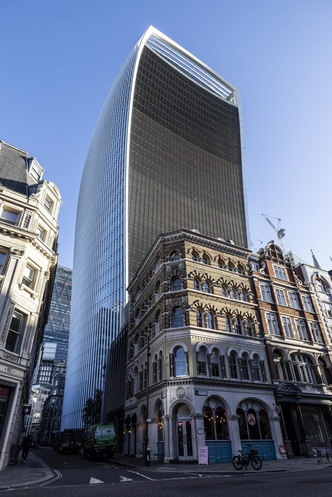 Modern skyscraper towering over historic buildings in London city centre.