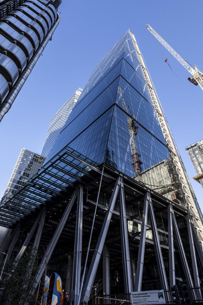 Modern glass skyscraper under construction in a city skyline.