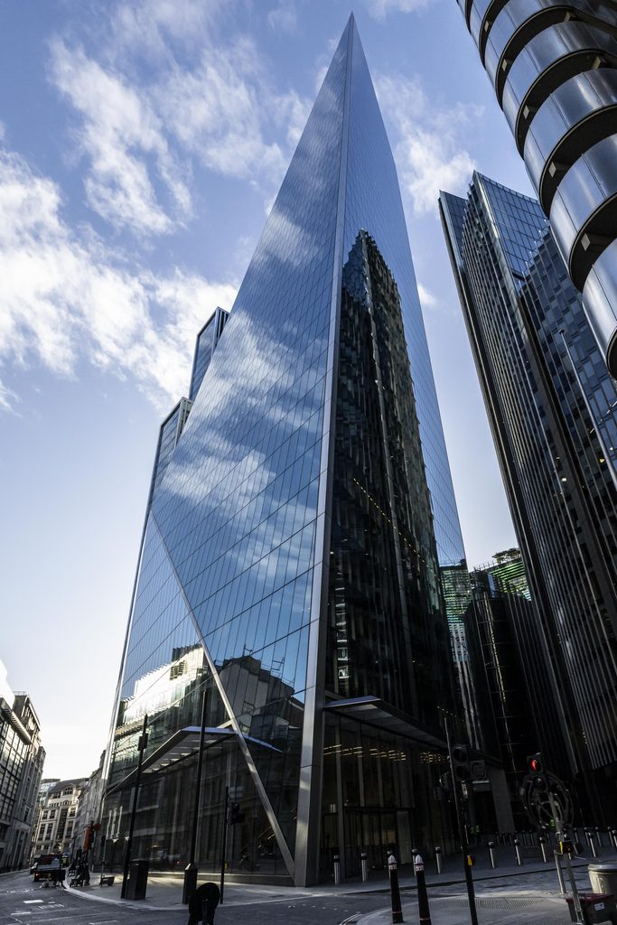 Modern glass skyscraper reflecting the sky and surrounding buildings in London.