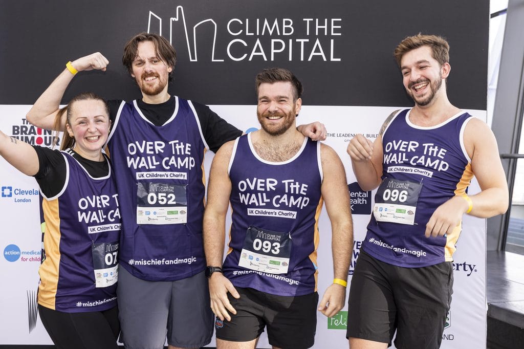 Group of four smiling participants at Over The Wall Camp climb event in London.