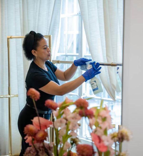 Cleaning Window with Spray Bottle Woman cleaning window with spray bottle and gloves in a bright room.