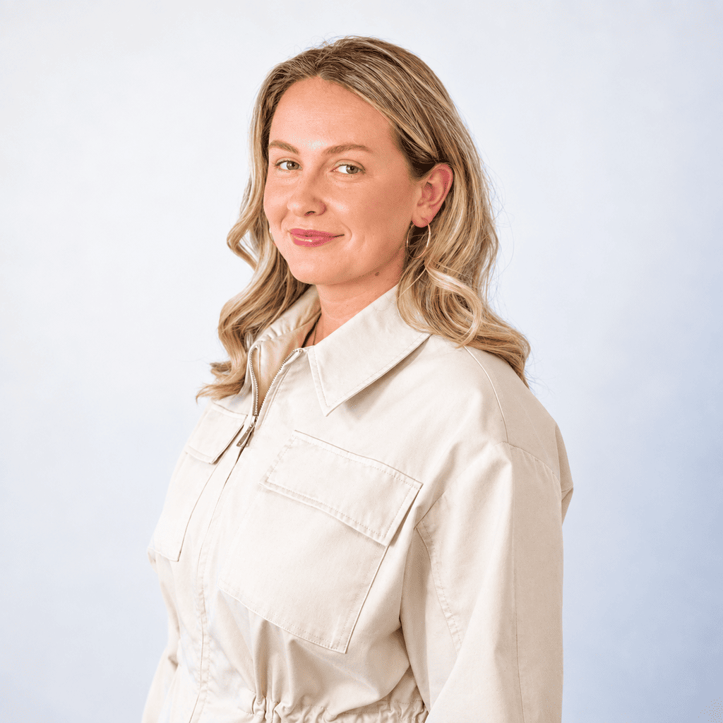 Confident woman smiling in a beige shirt for About Us page.