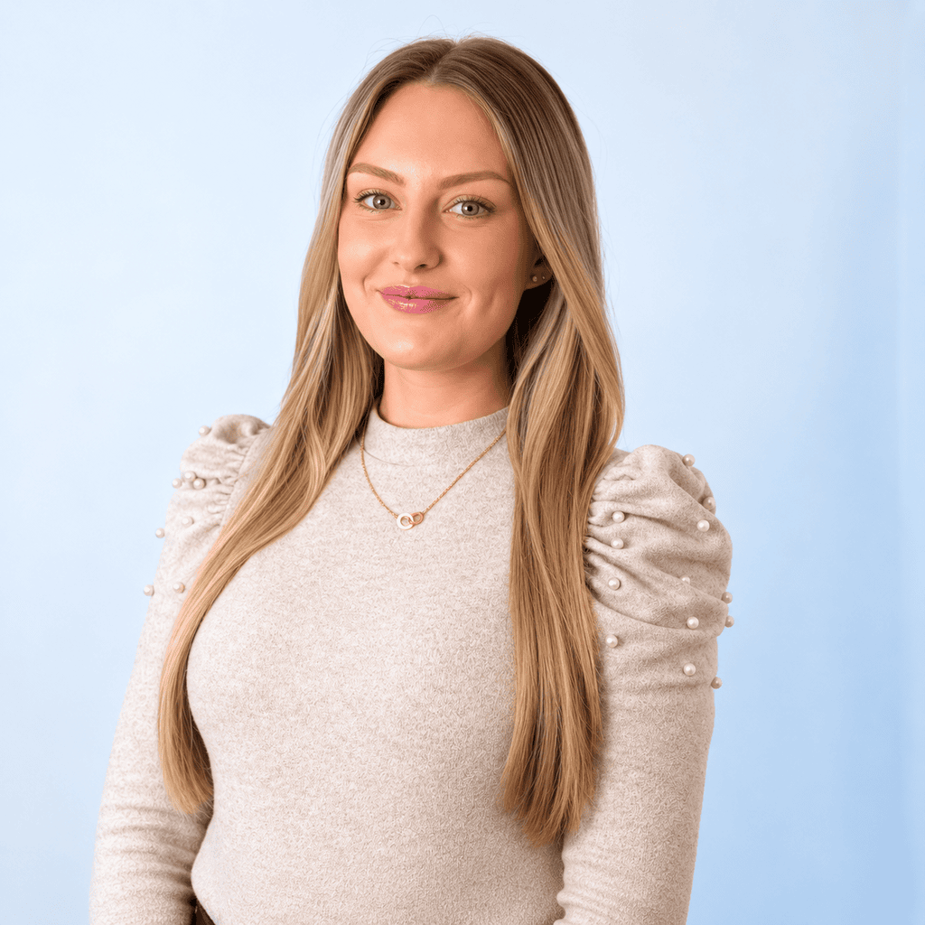 Confident woman with long blonde hair in a beige sweater for About Us page.